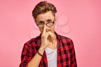 Serious man in glasses, pink background, emotion. Face expression, male person looking on camera in studio, emotional concept, feelings