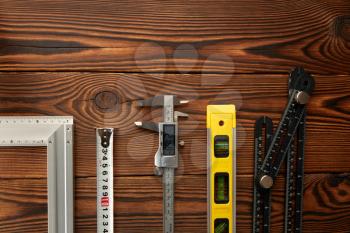Level and corner, ruler and caliper, wooden background, top view, nobody. Professional measuring instrument, carpenter equipment, woodworker tools