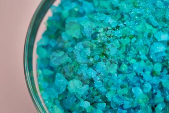 Blue sea salt in glass bowl, closeup view, pink background, nobody. Health care procedures concept, mineral hygiene products, spa therapy