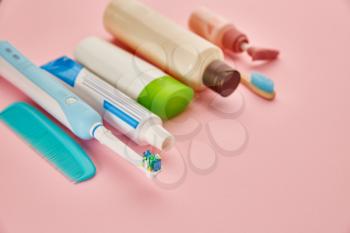 Oral and skin care products, pink background, nobody. Morning healthcare procedures concept, toothcare, toothbrush and toothpaste, brush and cream in bottle