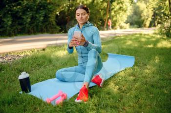 Morning fit training on mat in park, woman in headphones. Female runner goes in for sports at sunny day, healthy lifestyle, jogger on outdoors workout