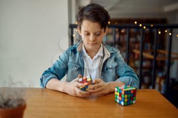 Little boy trying to solve puzzle cube. Toy for brain and logical mind training, creative game, solving of complex problems