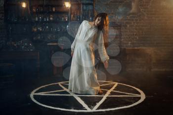 Creepy demonic woman standing in the magic circle, demons casting out. Exorcism, mystery paranormal ritual, dark religion, night horror, potions on shelf on background
