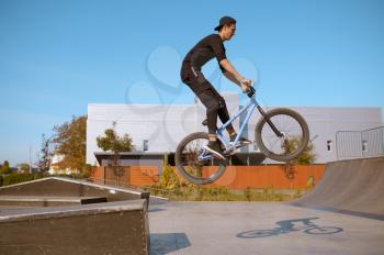 Male bmx biker, jump in action, teenager on training in skatepark. Extreme bicycle sport, dangerous cycle exercise, risk street riding, biking in summer park