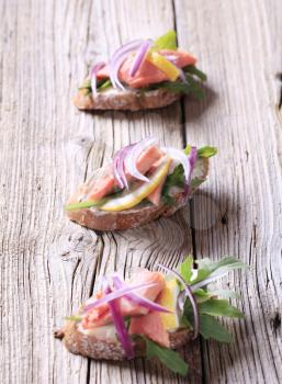Salmon open faced sandwiches garnished with red onion and lemon