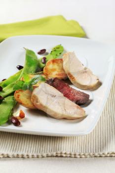 Slices of chicken and beef meat with potatoes and snow peas