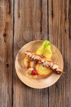 Chicken skewer and slices of roasted potato