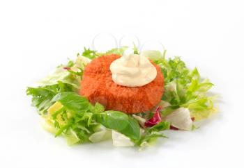 Fried breaded cheese or fish cake with green salad and mayonnaise