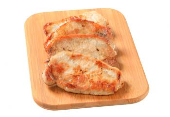 Pan seared pork cutlets on cutting board
