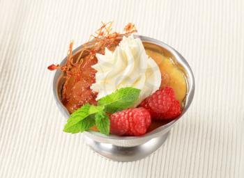 Creme brulee with raspberries and whipped cream in a metal serving dish