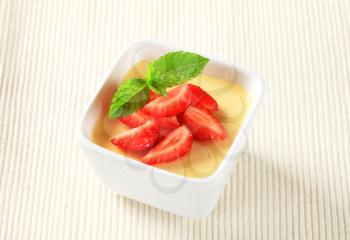 Small dish of vanilla pudding topped with strawberries