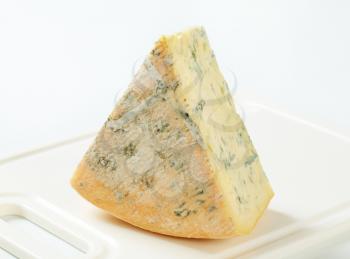 Large wedge of blue cheese on a cutting board