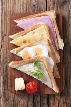 Ham, cheese and egg sandwiches on cutting board