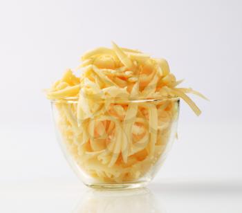 Grated yellow cheese in a glass cup 