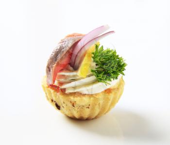 Pastry crust filled with savory spread topped with smoked fish