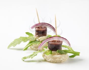 Anchovy canapes garnished with arugula and onion