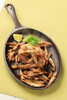 Crispy fried anchovies and roast potato on a frying pan