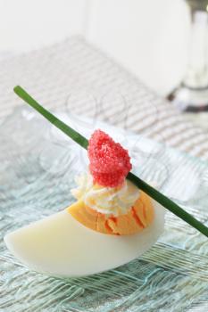 Boiled egg topped with spread and red caviar