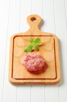 Raw meat patty on a cutting board