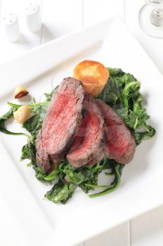 Slices of roast beef with sauteed spinach