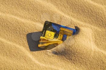 Close up of a credit card left in the sand
