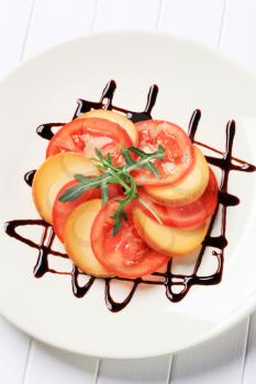 Sliced tomato and smoked cheese garnished with balsamic vinegar