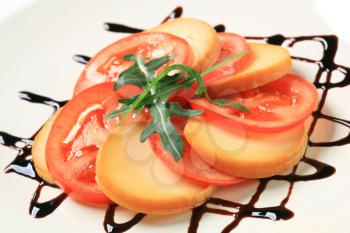 Sliced tomato and smoked cheese garnished with balsamic vinegar