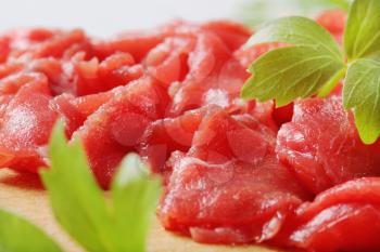 Thinly sliced raw beef meat on cutting board