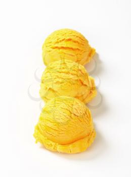 Three scoops of yellow ice cream arranged in a row