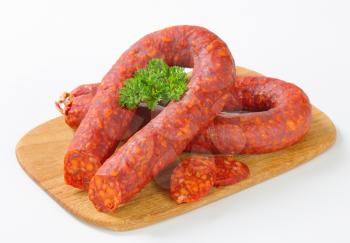 Spicy dry sausages on wooden cutting board