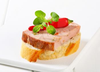 Slice of spicy meat loaf on crispy bread roll