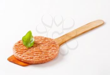 Raw burger patty on wooden spatula