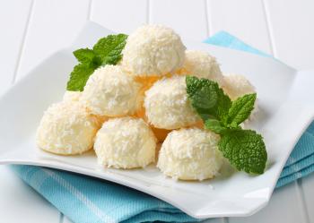 Pile of coconut snowball truffles on square plate