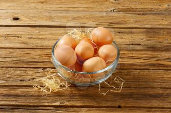 Brown eggs in a glass bowl
 on wooden background