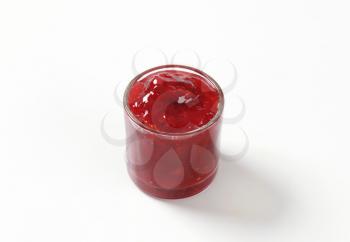 glass of strawberry jam on white background