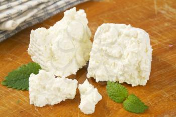 pieces of fresh curd cheese on cutting board