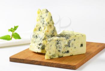Two wedges of French blue cheese on cutting board