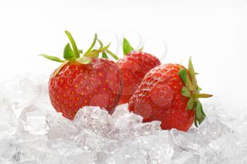 close up of three fresh strawberries on ice
