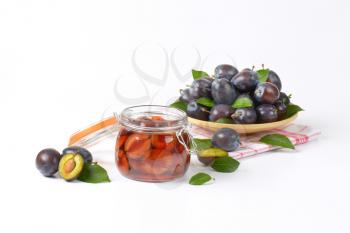 plum compote in a preserving jar and plate of fresh plums