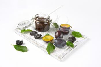 plum jam, fresh and dried plums on wooden cutting board