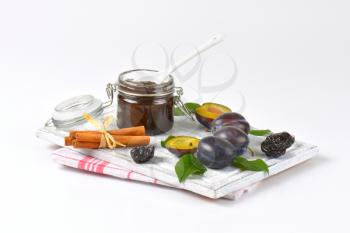 plum jam, cinnamon, fresh and dried plums on wooden cutting board