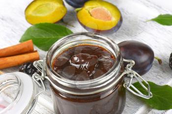 plum jam in a jar, fresh plums and cinnamon sticks
