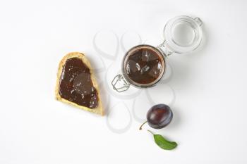 plum preserve in a jar and spread on a piece of baguette