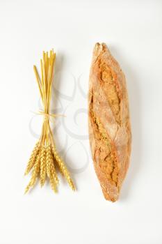 long loaf of whole grain bread and grain ears
