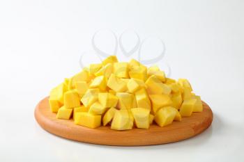 pile of pumpkin pieces on a round wooden cutting board