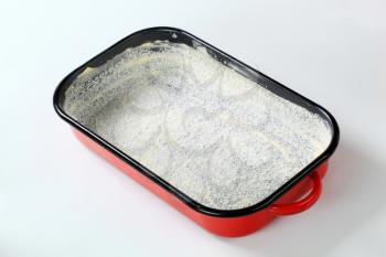 greased baking tin covered with desiccated coconut