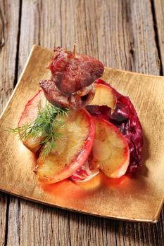Roasted meat on stick and slices of apple