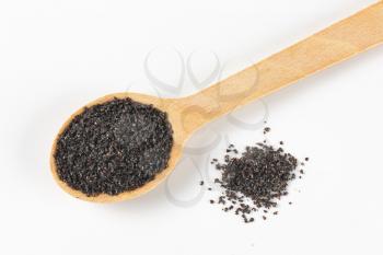 ground ripe poppy seeds on small wooden spoon