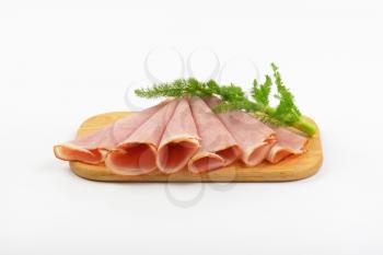 thin ham slices with dill on wooden cutting board