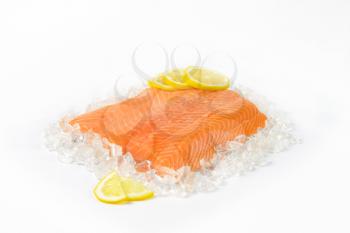 raw salmon fillet with slices of lemon on ice
